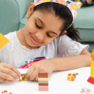 young girl plays with Legos at a table